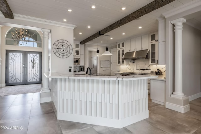 kitchen with white cabinets, pendant lighting, decorative backsplash, and a notable chandelier