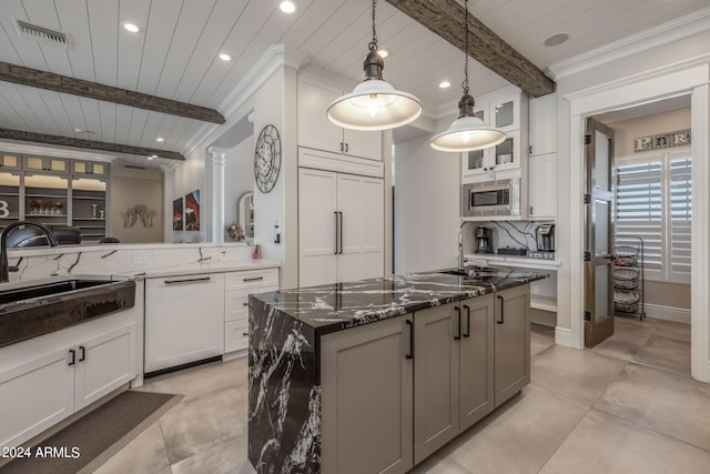 kitchen featuring dark stone counters, sink, built in appliances, beam ceiling, and white cabinetry