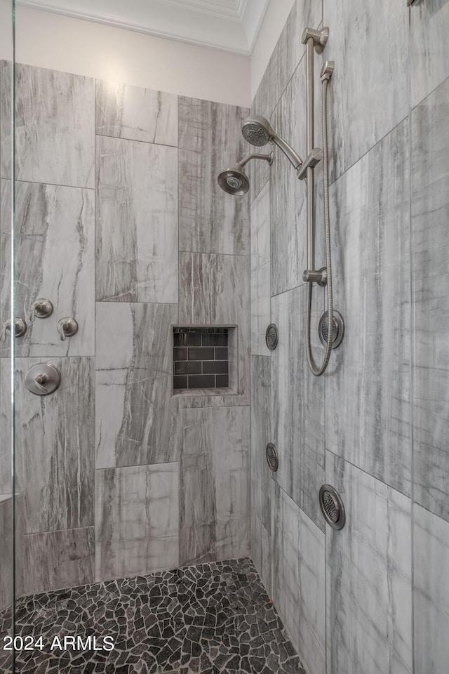 bathroom featuring a tile shower and ornamental molding