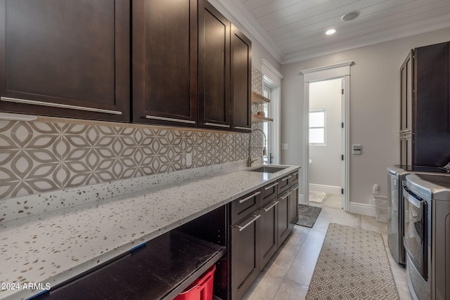 kitchen with sink, separate washer and dryer, light stone counters, backsplash, and dark brown cabinets