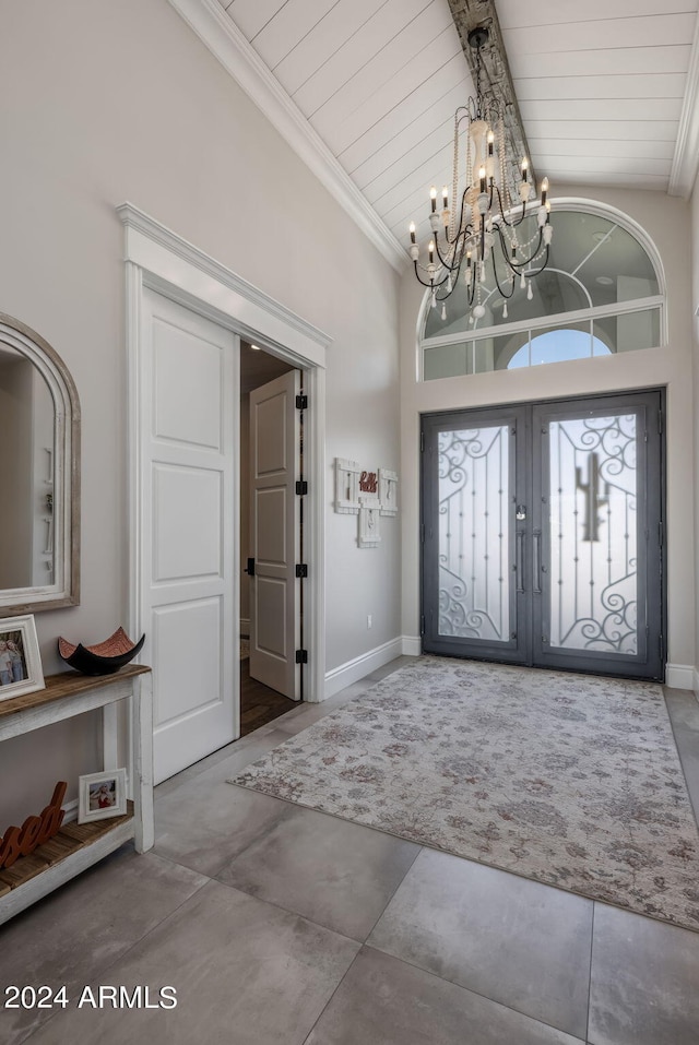 entrance foyer featuring a notable chandelier, french doors, high vaulted ceiling, and concrete floors