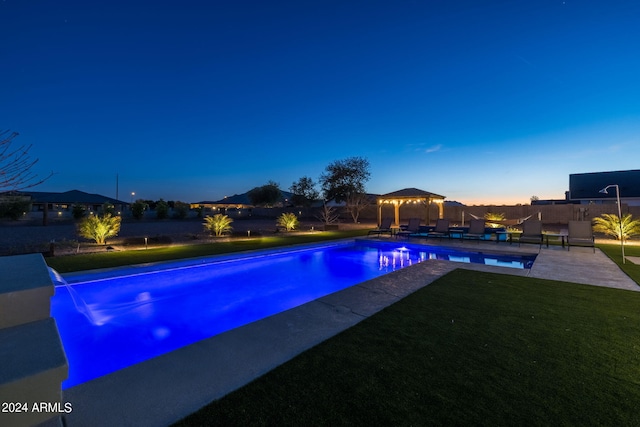 pool at dusk featuring a gazebo, a yard, and a patio