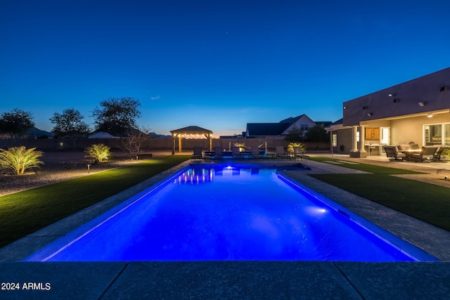 pool at dusk featuring a gazebo and a patio