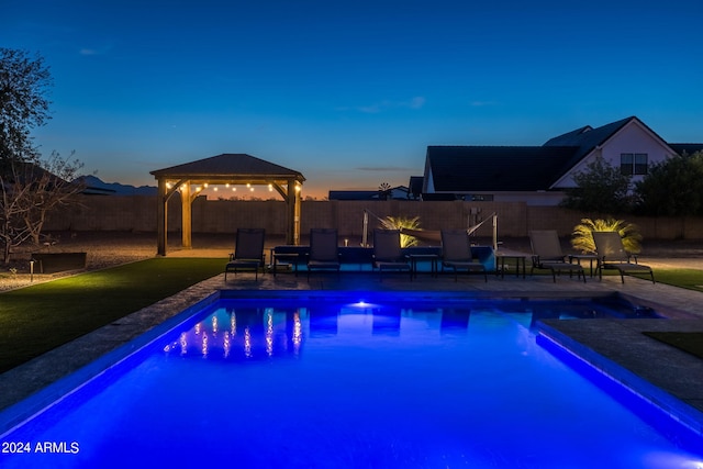 pool at dusk with a gazebo and a patio