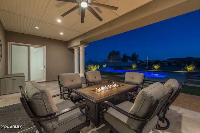 patio at night featuring ceiling fan and a fire pit