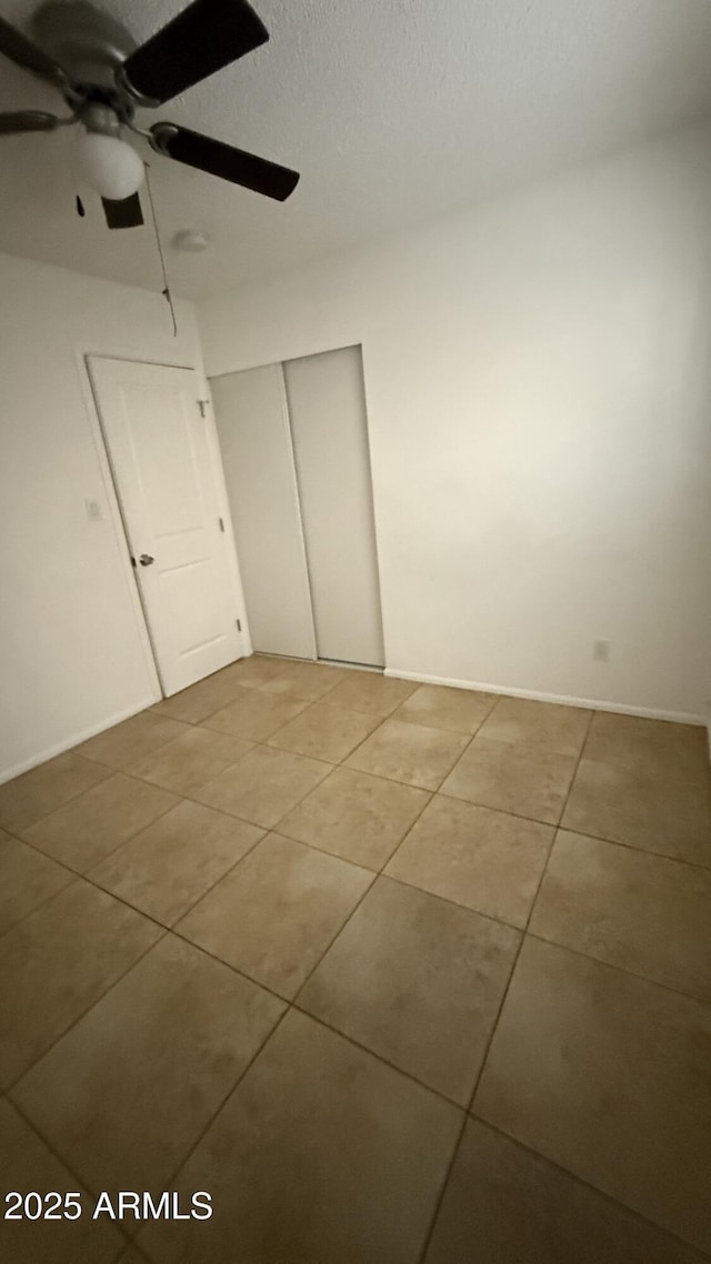 4217 W Medlock Dr, Phoenix, AZ 85019 - unfurnished bedroom featuring light tile patterned flooring, a closet, a textured ceiling, and ceiling fan