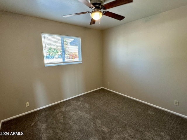 spare room featuring ceiling fan and dark carpet