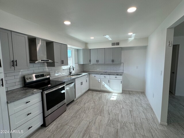 kitchen with tasteful backsplash, wall chimney exhaust hood, stainless steel appliances, sink, and gray cabinets