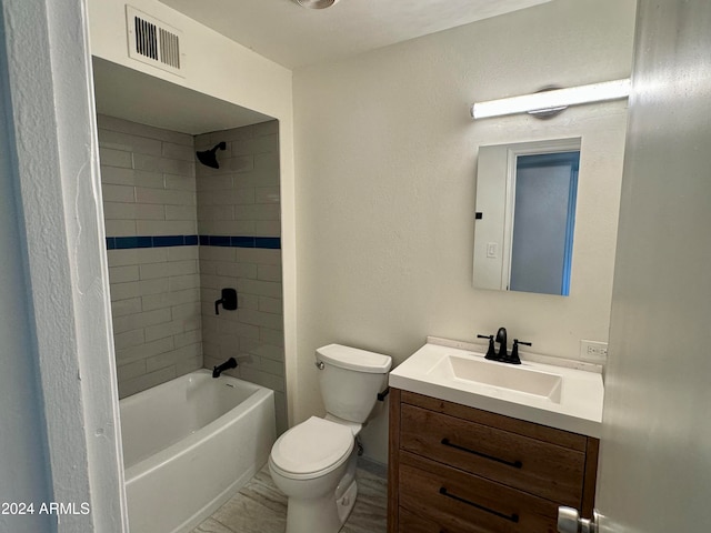 full bathroom featuring vanity, tiled shower / bath combo, and toilet