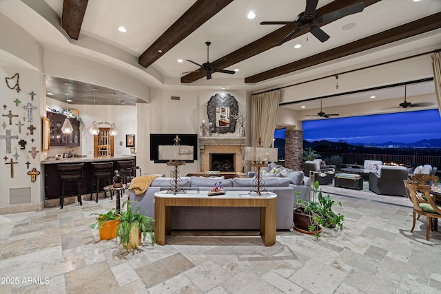 6102 E Sage Dr, Paradise Valley, AZ 85253 - living area with bar area, stone tile floors, beam ceiling, ceiling fan, and a fireplace