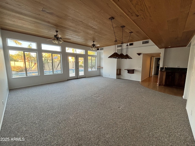 unfurnished living room featuring ceiling fan, carpet flooring, and wooden ceiling