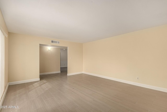 unfurnished room featuring visible vents, baseboards, and wood finished floors