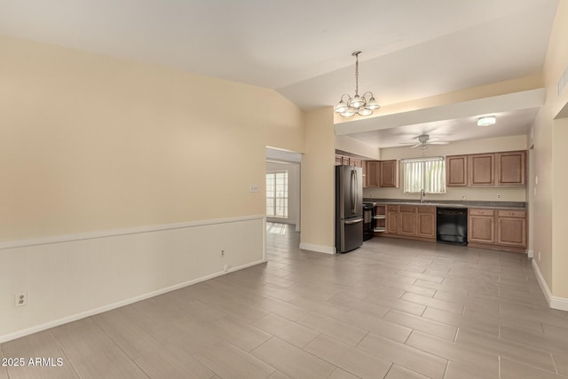 kitchen with lofted ceiling, ceiling fan with notable chandelier, a sink, black dishwasher, and freestanding refrigerator