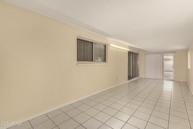 spare room featuring light tile patterned floors and brick wall