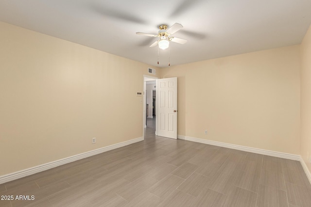 empty room with a ceiling fan, visible vents, baseboards, and wood finished floors