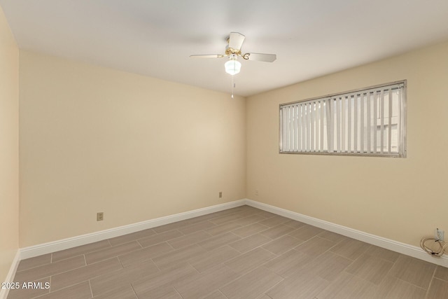 unfurnished room featuring ceiling fan and baseboards