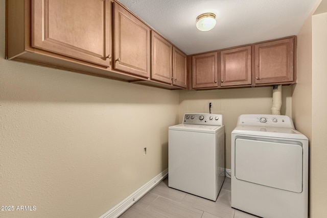 laundry room featuring cabinet space, baseboards, and separate washer and dryer