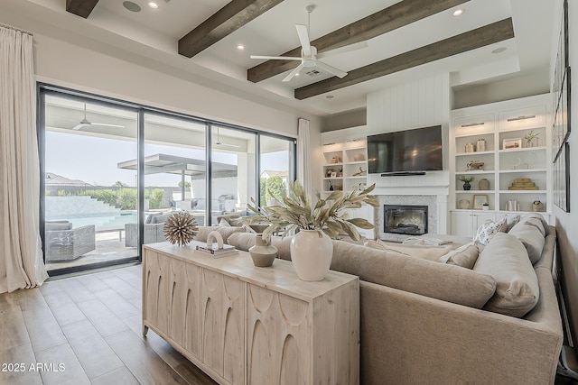 living room with a ceiling fan, a glass covered fireplace, beam ceiling, and recessed lighting