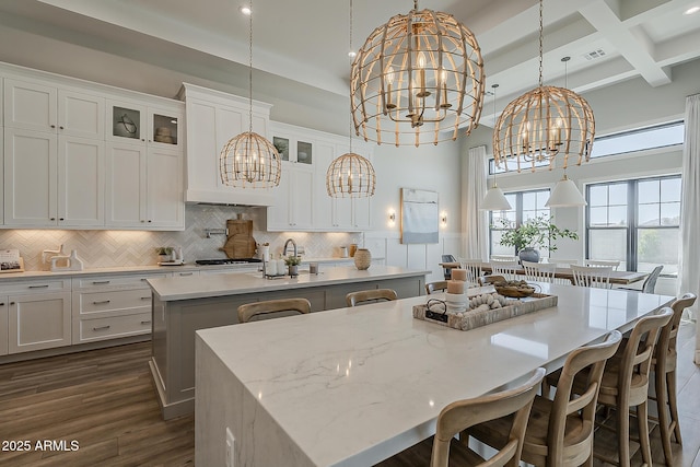 kitchen featuring a kitchen breakfast bar, a kitchen island with sink, white cabinetry, and a chandelier