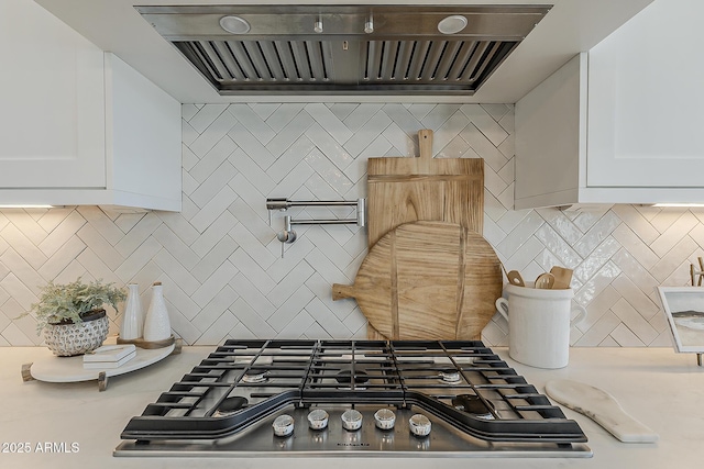 kitchen featuring backsplash, stainless steel gas stovetop, custom range hood, and light countertops