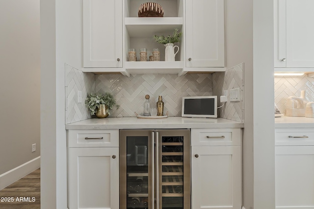 bar with a dry bar, beverage cooler, baseboards, wood finished floors, and backsplash