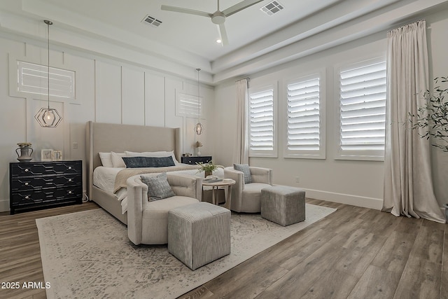 bedroom with baseboards, a ceiling fan, wood finished floors, and visible vents