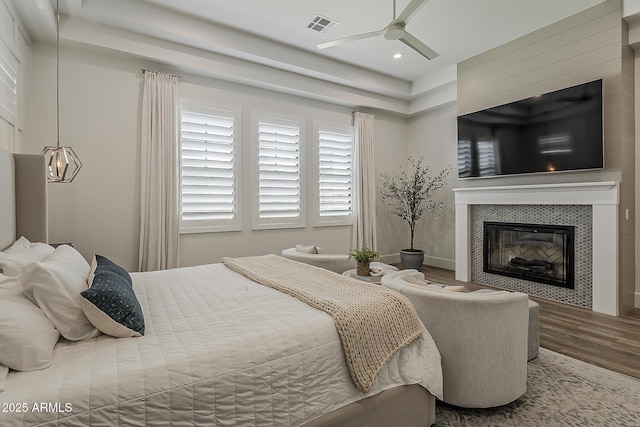 bedroom featuring ceiling fan, recessed lighting, wood finished floors, a tile fireplace, and visible vents