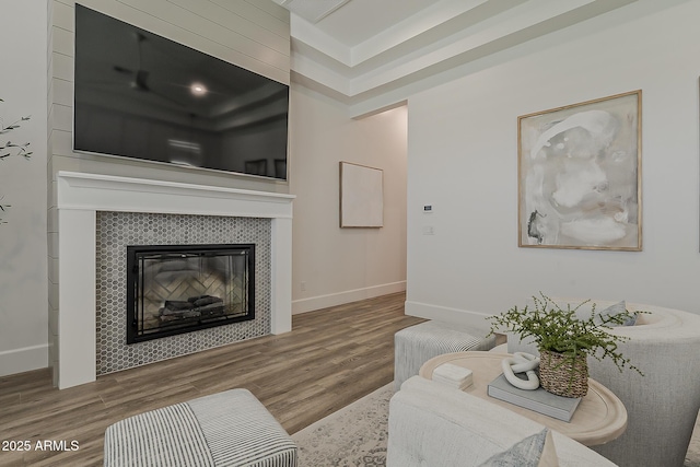 living area with baseboards, wood finished floors, and a fireplace