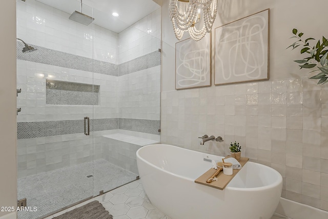 bathroom with a freestanding tub, a shower stall, a notable chandelier, and tile walls