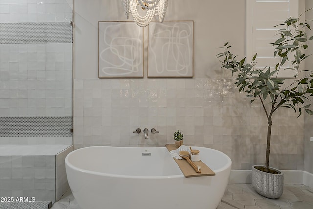 bathroom with a chandelier, tile patterned floors, tile walls, and a freestanding tub