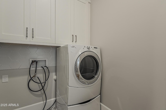 laundry area featuring baseboards, cabinet space, and washer / clothes dryer