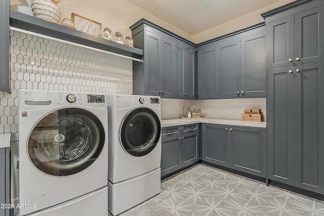 clothes washing area featuring light floors, cabinet space, and washing machine and clothes dryer