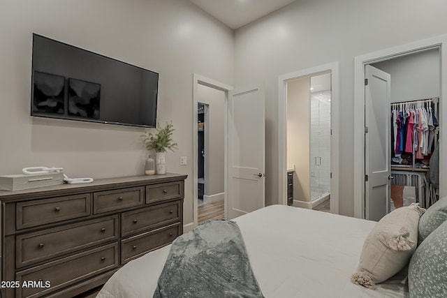 bedroom featuring wood finished floors, a closet, connected bathroom, and a spacious closet