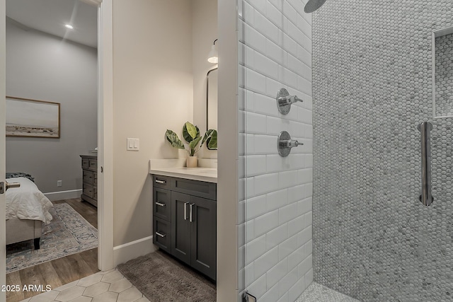 bathroom featuring wood finished floors, tiled shower, ensuite bathroom, and vanity