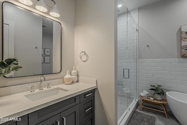 full bath featuring vanity, tile walls, a freestanding bath, and a stall shower