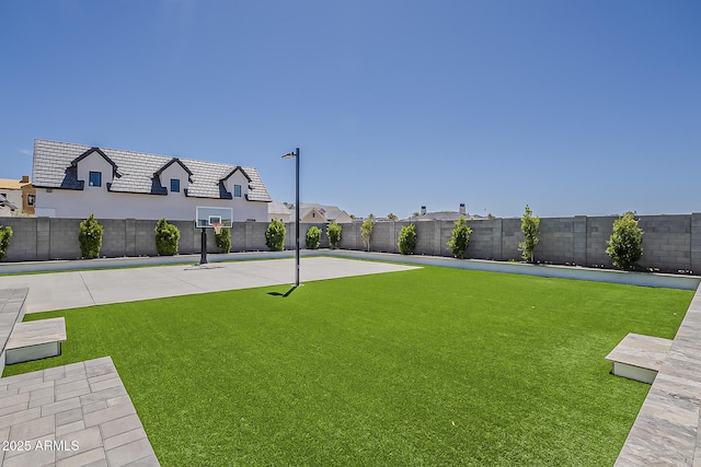 view of yard featuring basketball hoop and a fenced backyard