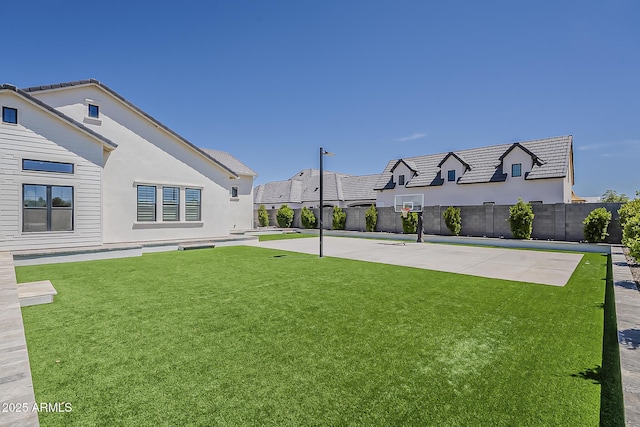 view of yard with basketball court and fence