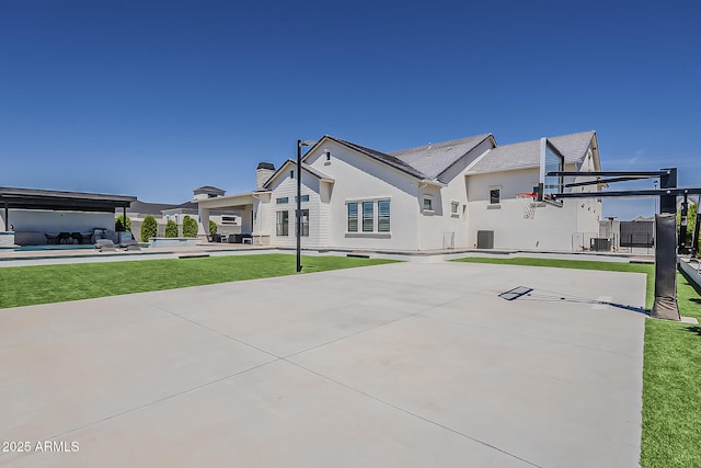 view of basketball court featuring a lawn and basketball hoop