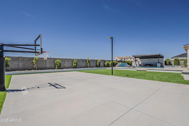 view of basketball court featuring basketball hoop, fence, a lawn, and a swimming pool