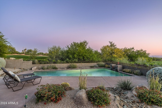 pool at dusk featuring a patio area