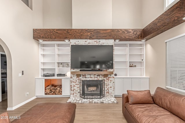 3514 E Desert Willow Rd, Phoenix, AZ 85044 - living room featuring arched walkways, wood finished floors, a brick fireplace, a towering ceiling, and baseboards