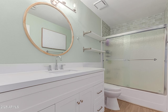 3514 E Desert Willow Rd, Phoenix, AZ 85044 - bathroom with toilet, vanity, wood finished floors, and bath / shower combo with glass door