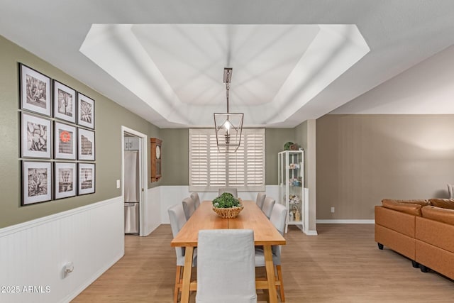 3514 E Desert Willow Rd, Phoenix, AZ 85044 - dining area featuring a tray ceiling, light wood-style flooring, and wainscoting