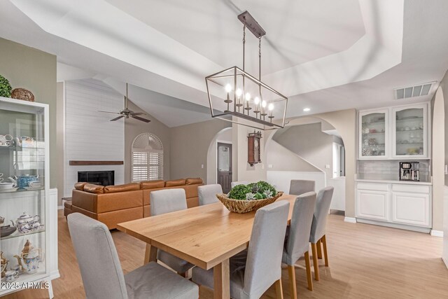 3514 E Desert Willow Rd, Phoenix, AZ 85044 - dining area featuring arched walkways, light wood-style flooring, a ceiling fan, vaulted ceiling, and a large fireplace