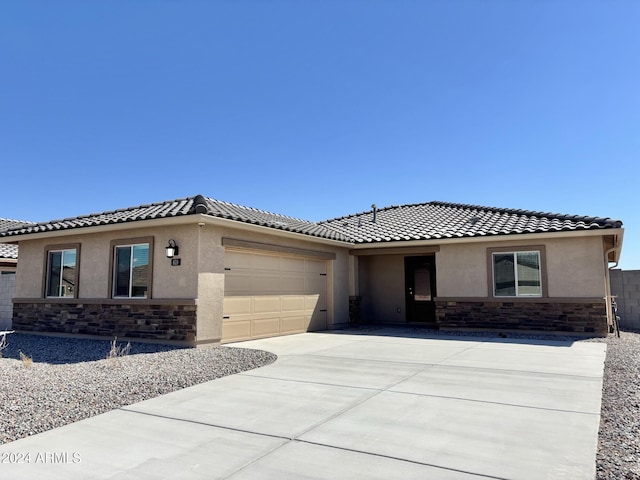 ranch-style house featuring an attached garage, stone siding, concrete driveway, and stucco siding