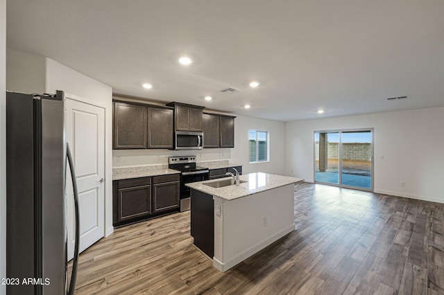 kitchen featuring a kitchen island with sink, stainless steel appliances, a sink, visible vents, and light wood-type flooring