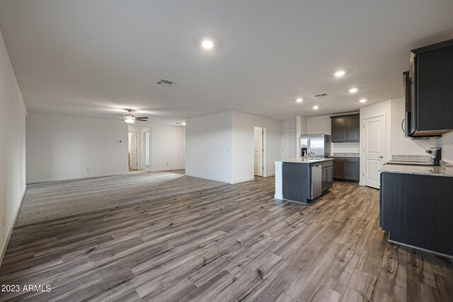 kitchen featuring hardwood / wood-style floors, ceiling fan, appliances with stainless steel finishes, an island with sink, and sink