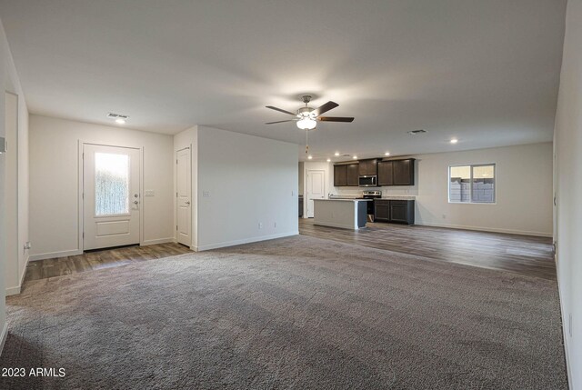 unfurnished living room with a ceiling fan, baseboards, visible vents, and carpet flooring