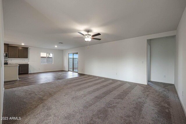 unfurnished living room with baseboards, dark colored carpet, a ceiling fan, and recessed lighting