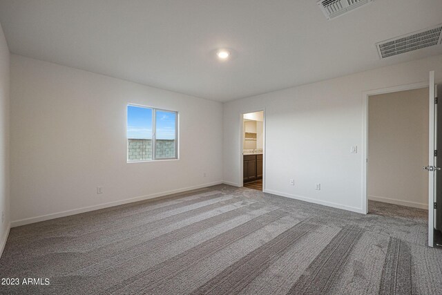 unfurnished bedroom with carpet floors, visible vents, connected bathroom, and baseboards